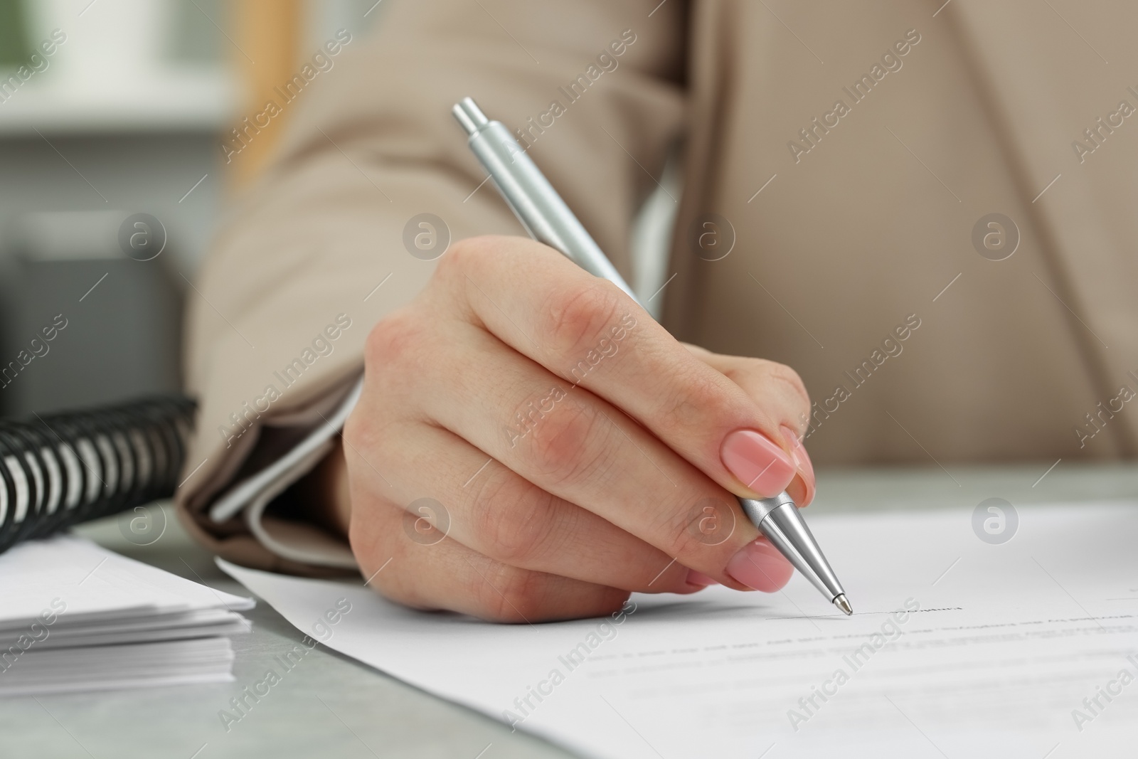 Photo of Woman signing document at table, closeup view