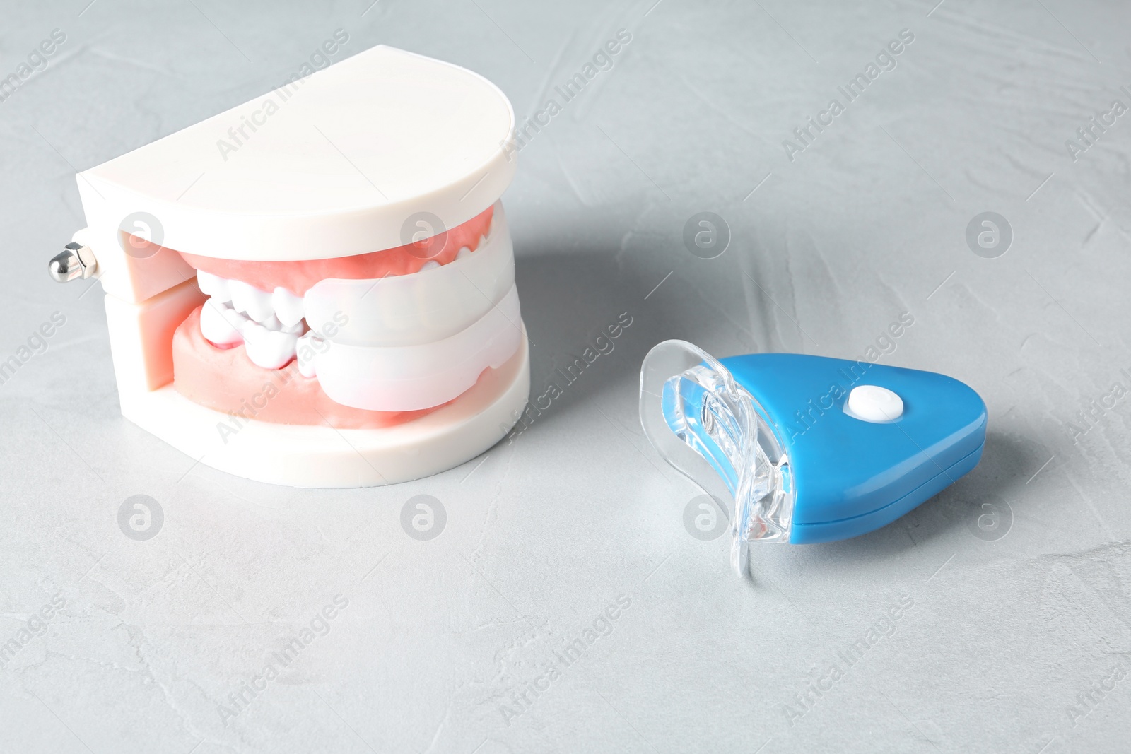 Photo of Educational model of oral cavity with teeth and whitening device on table