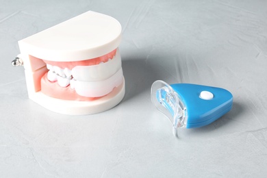 Photo of Educational model of oral cavity with teeth and whitening device on table