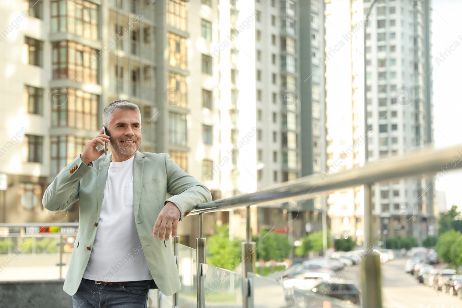 Photo of Handsome mature man talking on phone in city center. Space for text