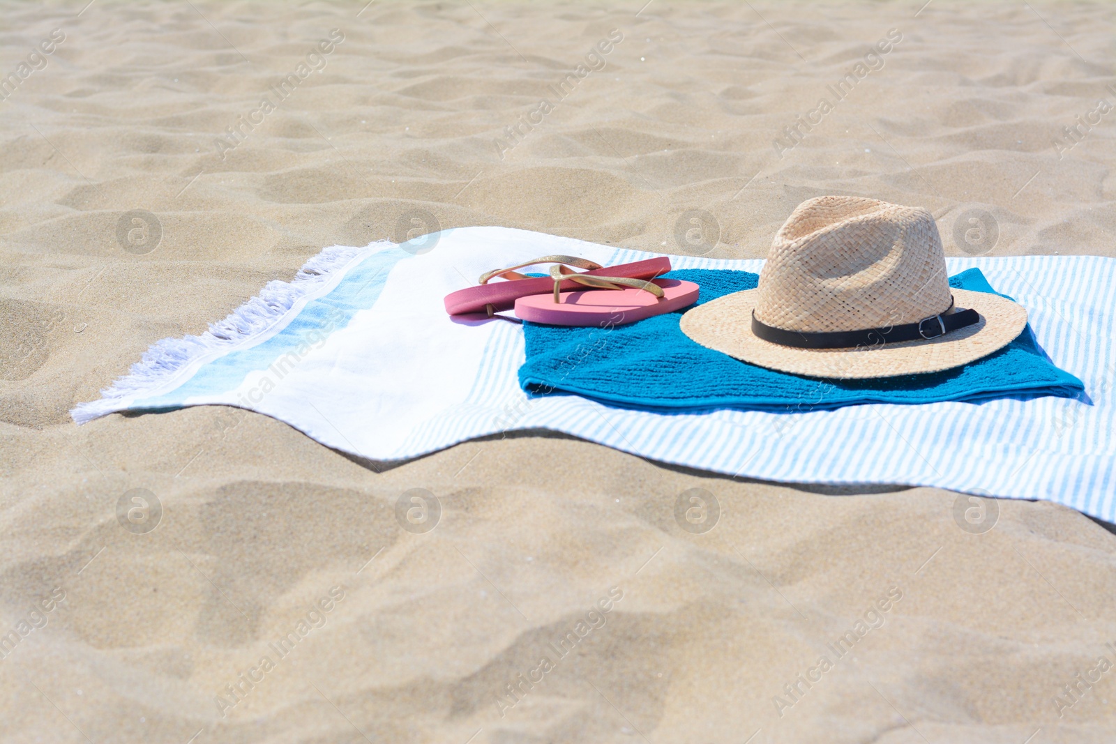 Photo of BLue towels, flip flops and straw hat on sandy beach