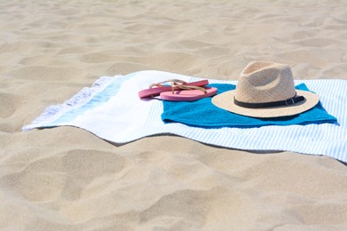 BLue towels, flip flops and straw hat on sandy beach