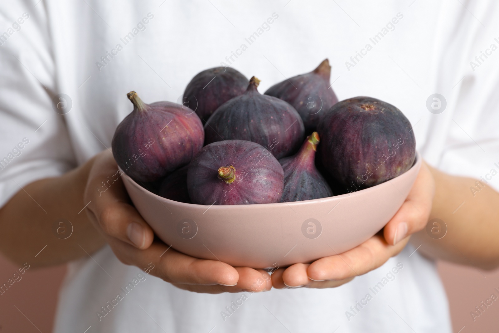 Photo of Woman holding bowl with tasty raw figs, closeup