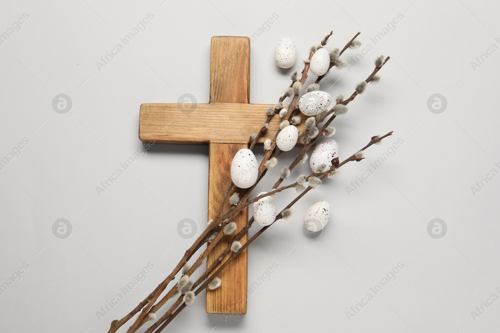 Photo of Wooden cross, painted Easter eggs and willow branches on light grey background, top view