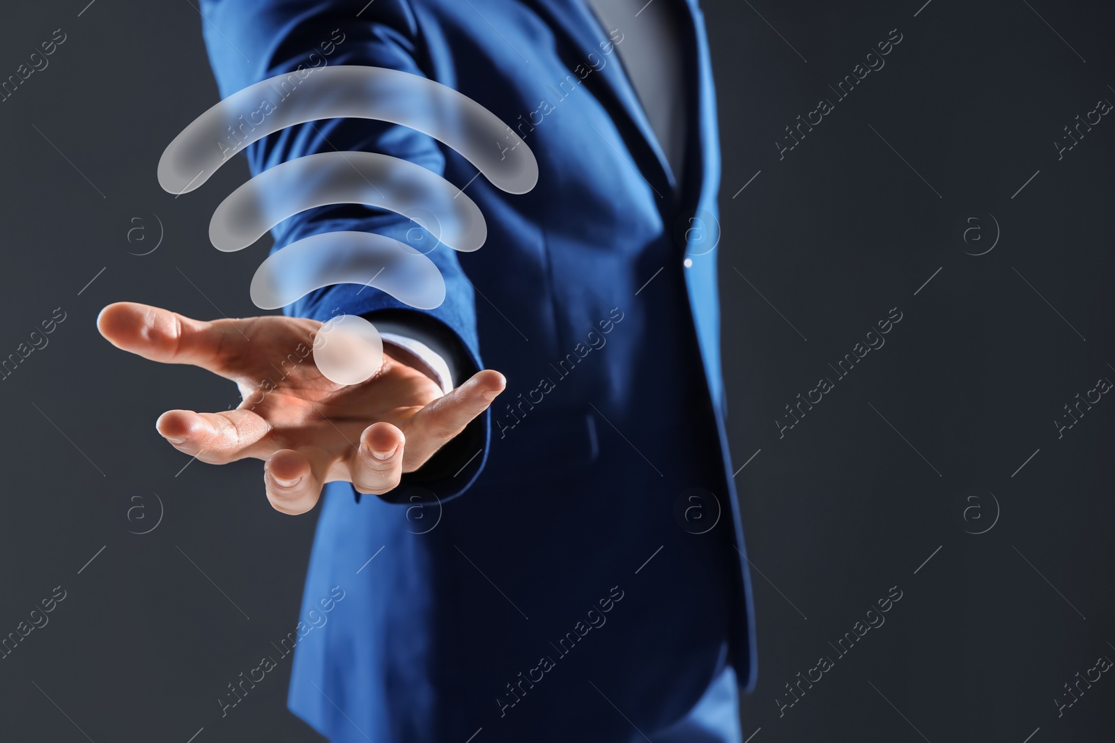 Image of Man holding Wi Fi symbol in hand on dark grey background, closeup