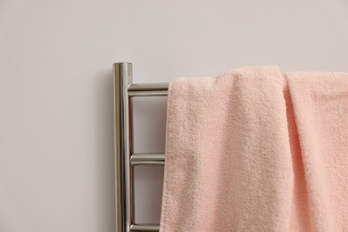 Photo of Heated rail with pink towel on white wall, closeup