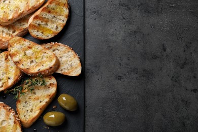 Tasty bruschettas with oil, thyme and olives on grey table, top view. Space for text