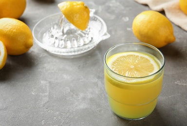 Photo of Glass with fresh lemon juice and fruits on table