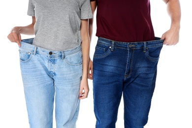 Fit people in oversized jeans on white background, closeup. Weight loss