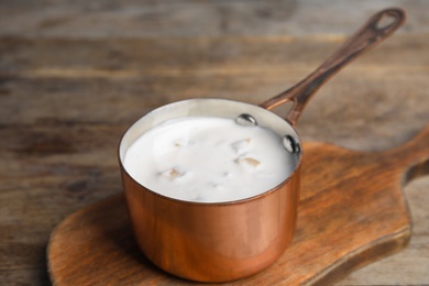 Photo of Delicious creamy sauce in pan on wooden table