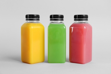 Photo of Bottles with delicious colorful juices on light background