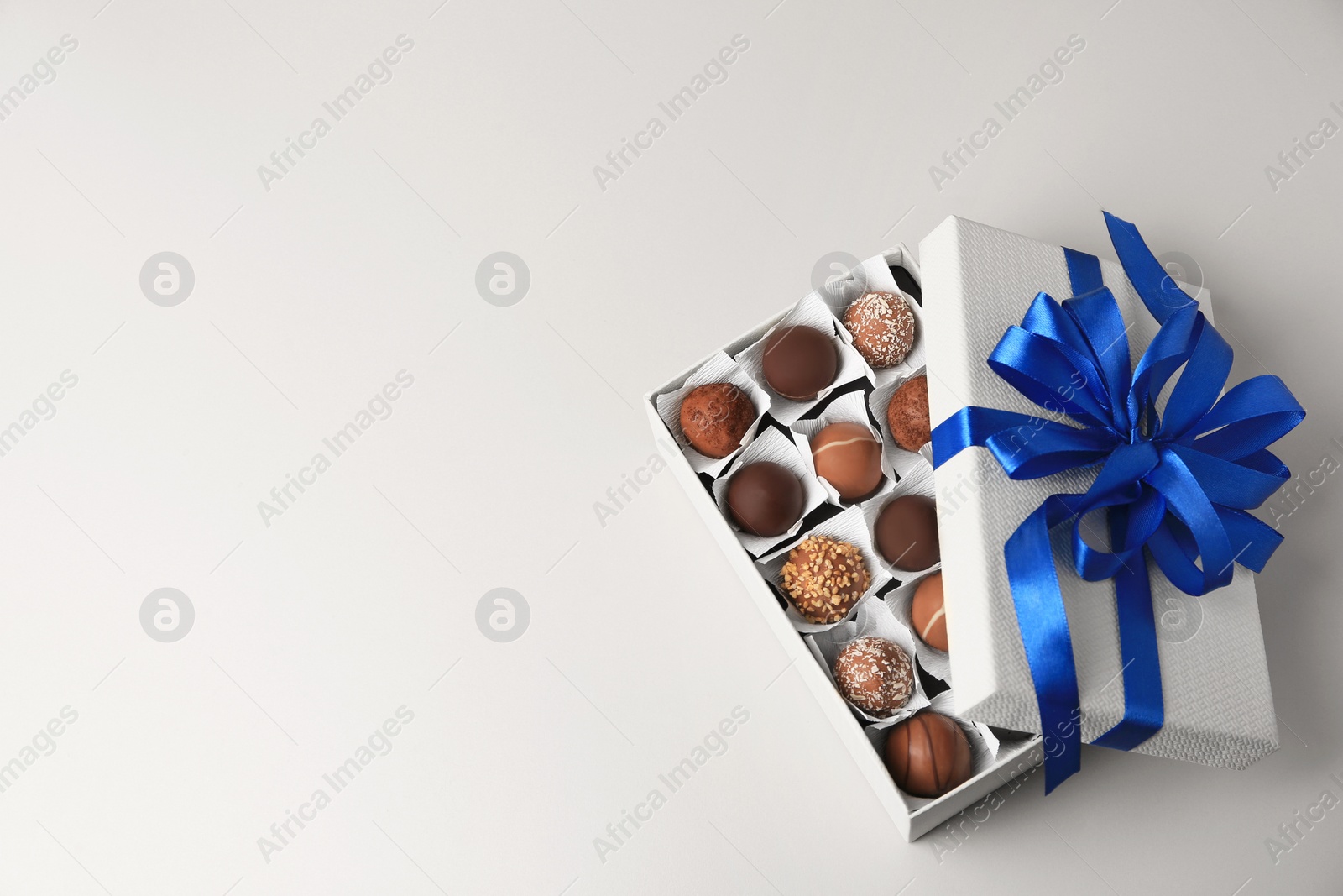 Photo of Box with delicious chocolate candies on beige background, top view. Space for text