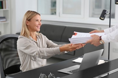 Photo of Man giving documents to happy colleague in office
