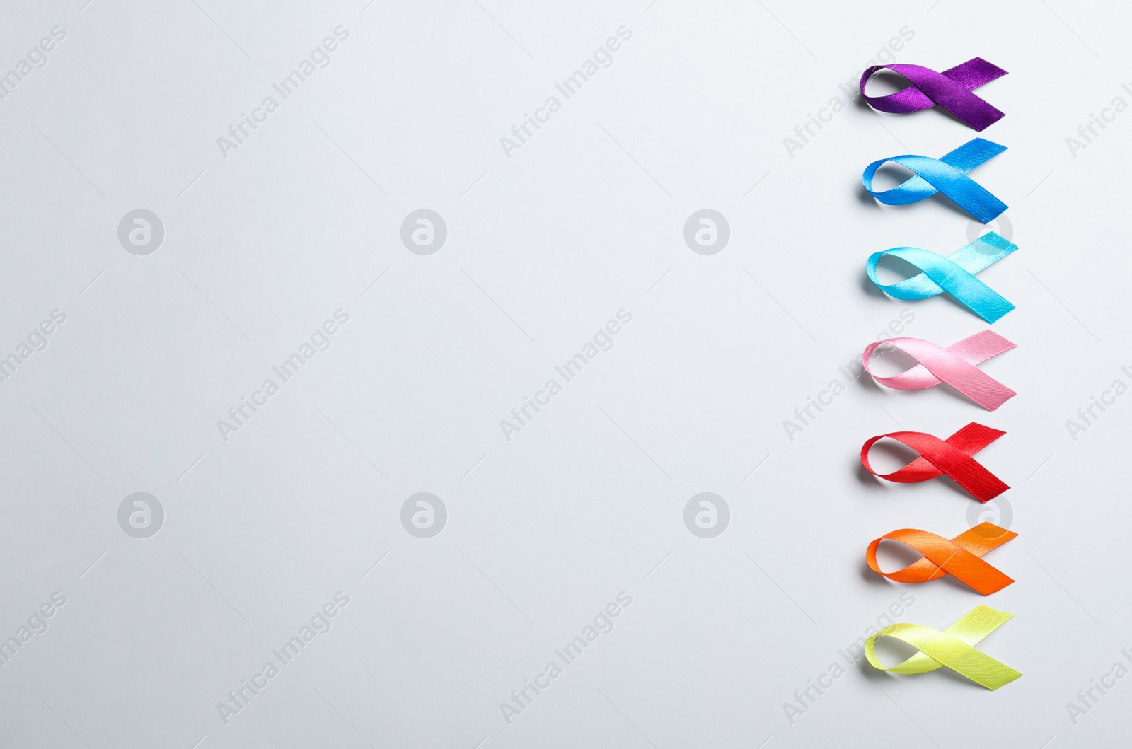 Photo of Different colorful ribbons on white background, flat lay with space for text. World Cancer Day