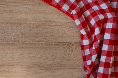 Photo of Checkered picnic cloth on wooden table, top view. Space for text