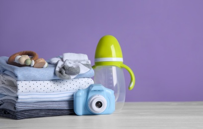 Children's accessories, toys and stack of clothes on white wooden table. Space for text