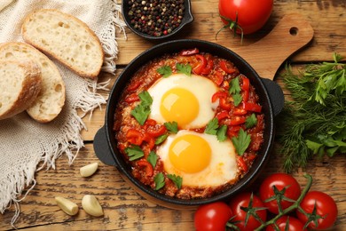 Photo of Delicious Shakshuka served on wooden table, flat lay