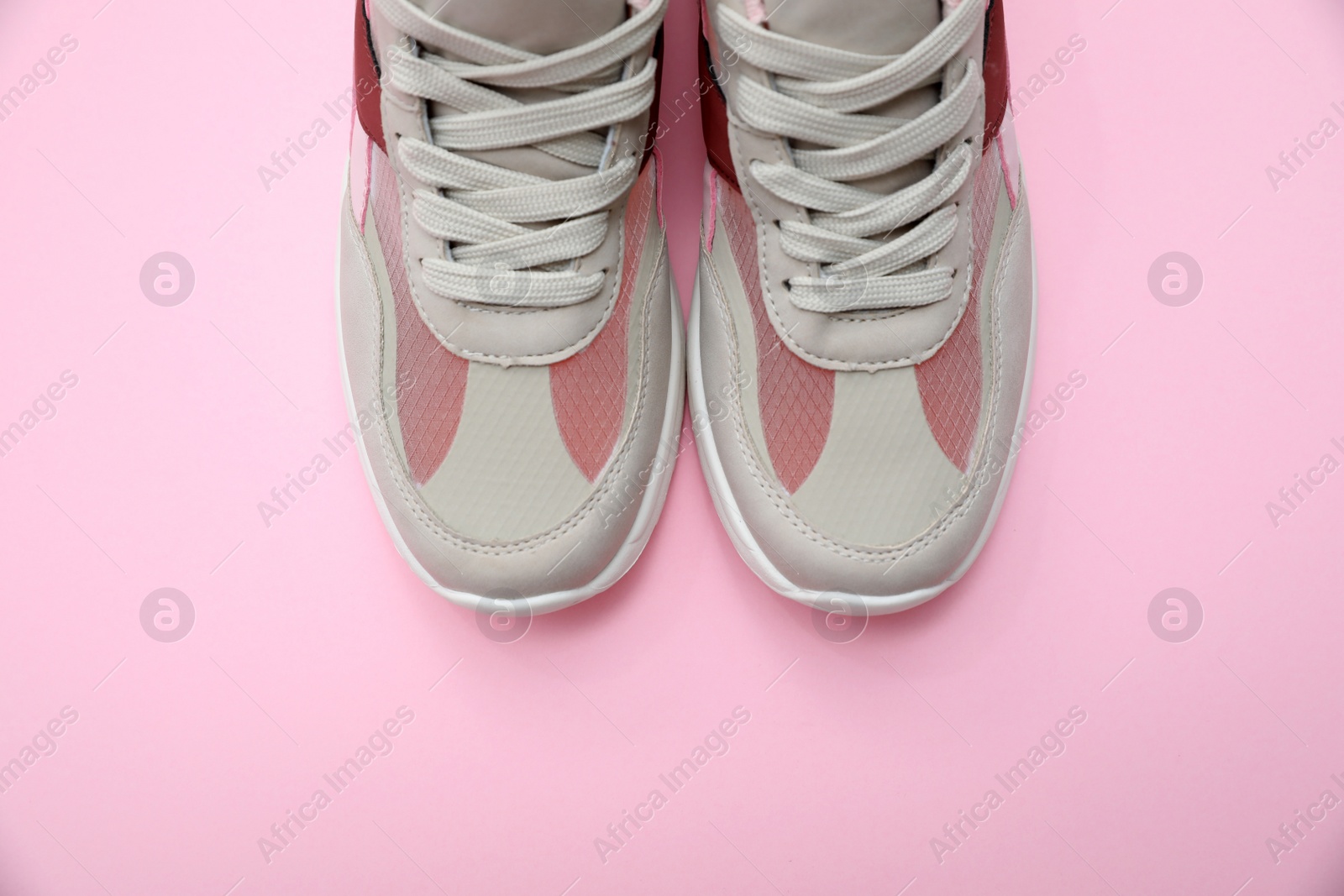 Photo of Pair of stylish women's sneakers on pink background, top view