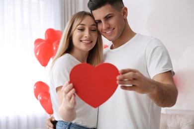 Photo of Lovely couple with gift in room. Valentine's day celebration