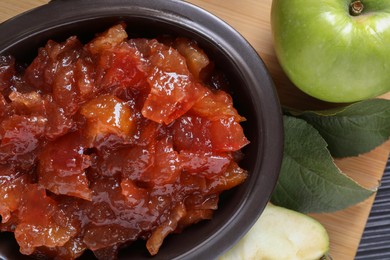 Bowl of delicious apple jam and fresh fruits on black wooden table, flat lay