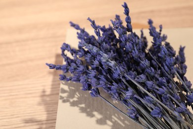 Photo of Bouquet of beautiful preserved lavender flowers and notebook on wooden table, closeup. Space for text