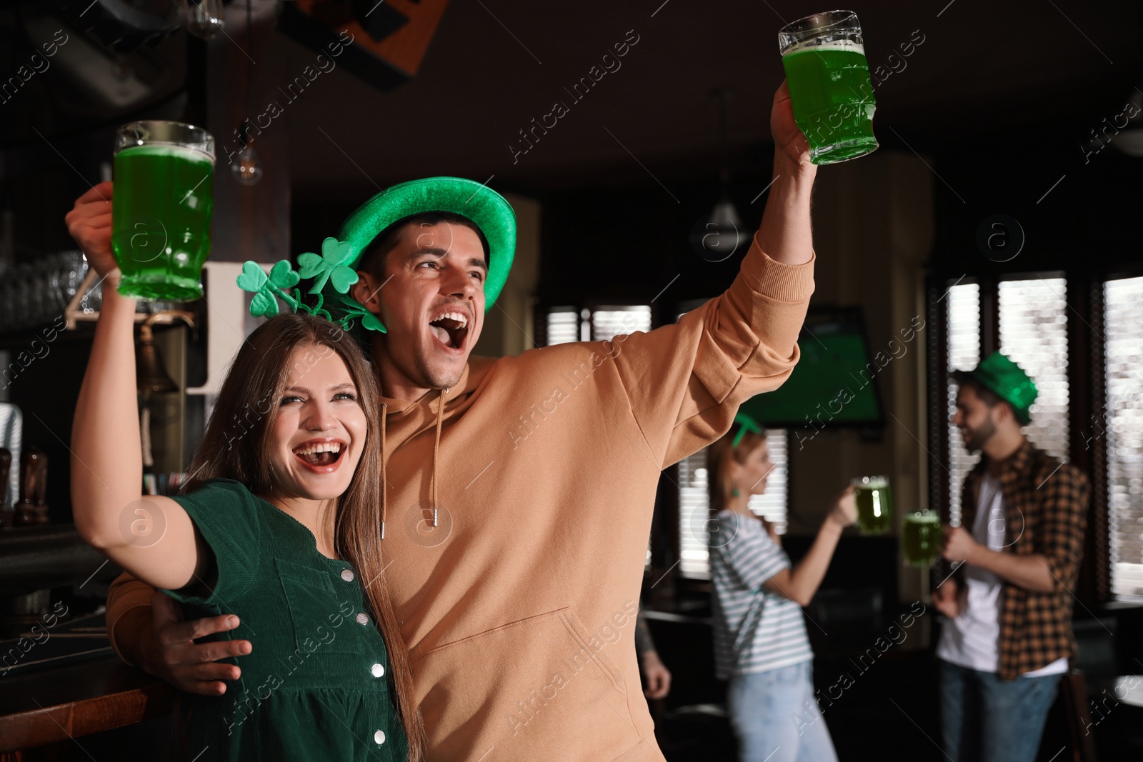 Photo of Young woman and man with glasses of green beer in pub.St. Patrick's Day celebration