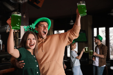 Photo of Young woman and man with glasses of green beer in pub.St. Patrick's Day celebration