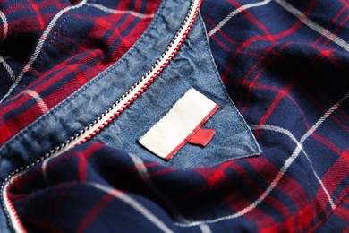 Photo of Blank clothing label on checkered shirt, closeup