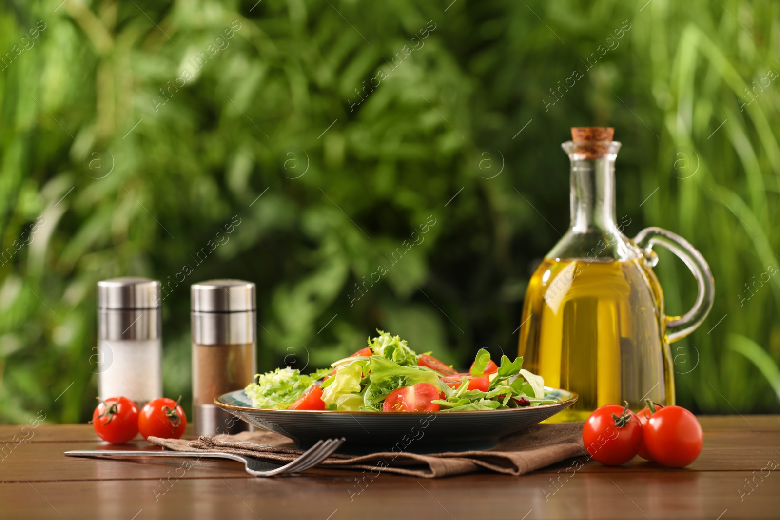 Photo of Delicious salad served on wooden table against blurred green background