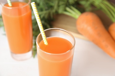 Photo of Freshly made carrot juice on white wooden table, closeup