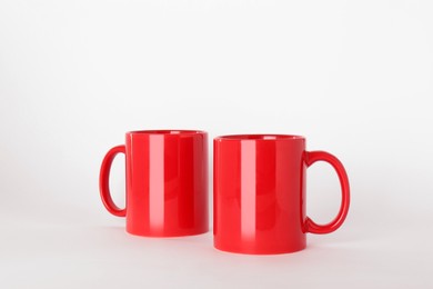 Photo of Blank red ceramic mugs on light background
