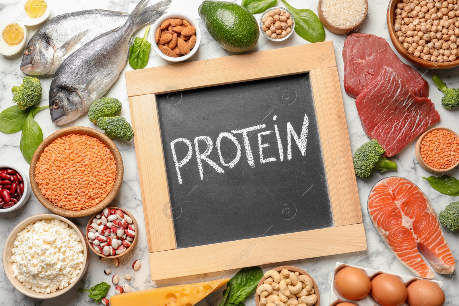 Photo of Set of natural food and chalkboard with written word Protein on marble background