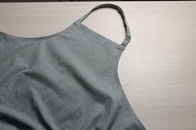 Photo of Stylish apron on white wooden table, above view. Mockup for design