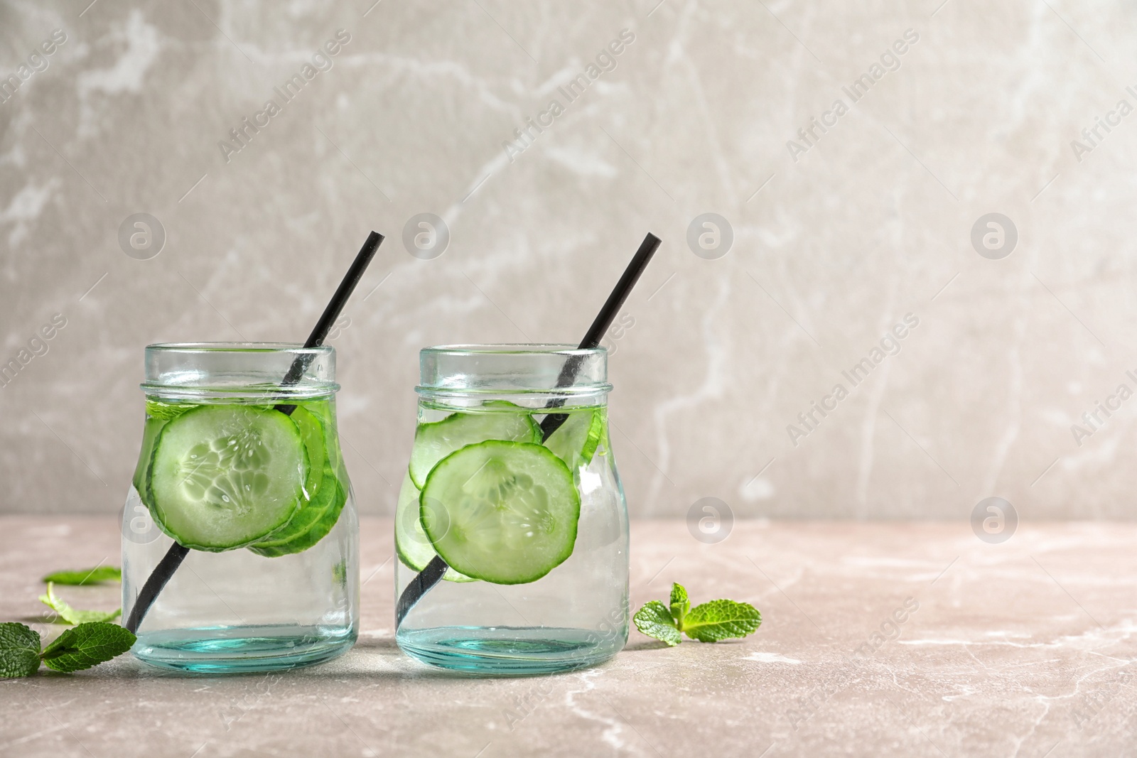 Photo of Jars with fresh cucumber water on table. Space for text