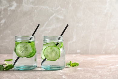 Photo of Jars with fresh cucumber water on table. Space for text