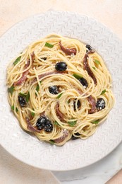 Delicious pasta with anchovies, olives and parmesan cheese on beige textured table, top view