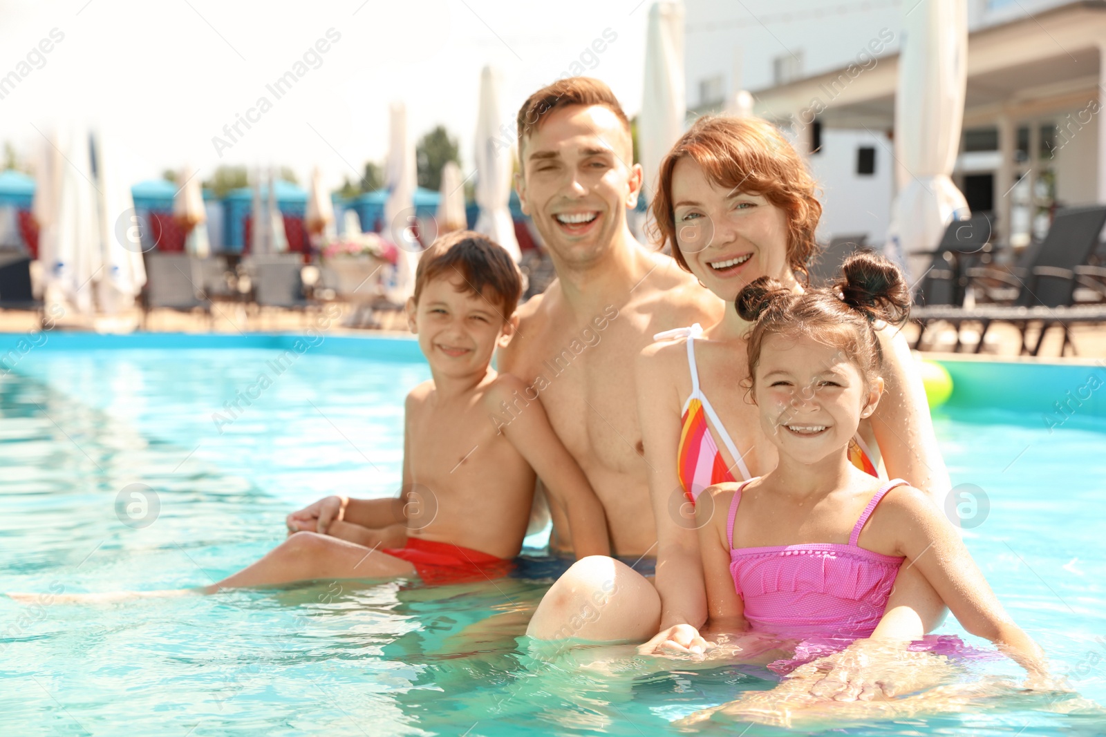 Photo of Happy family in swimming pool at resort