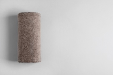 Photo of Fresh fluffy rolled towel on grey background, top view with space for text
