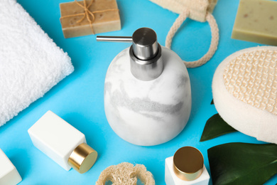 Photo of Marble soap dispenser and toiletries on light blue background