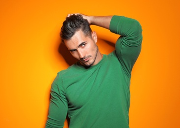 Young man with trendy hairstyle posing on color background