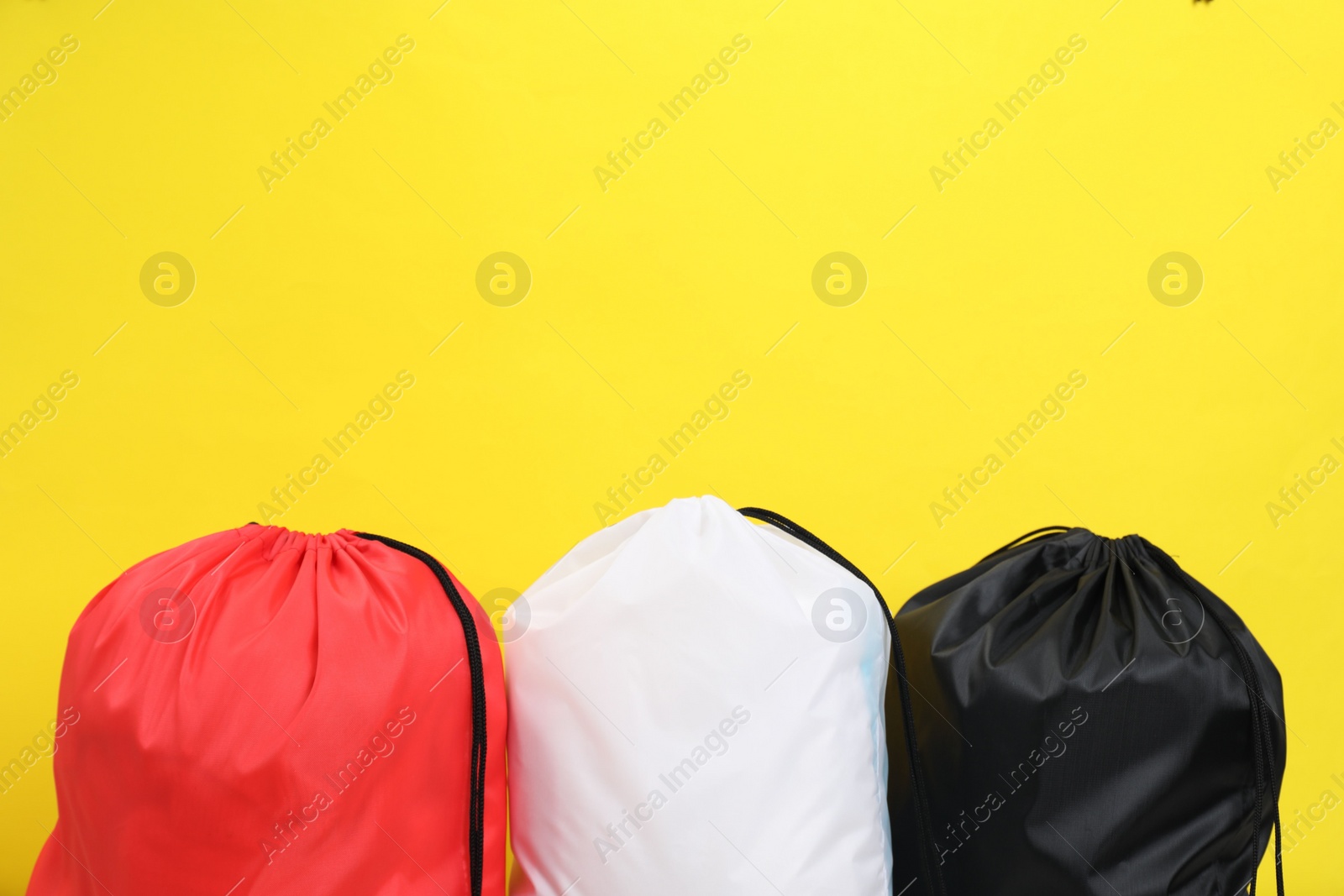 Photo of Three drawstring bags on yellow background. Space for text