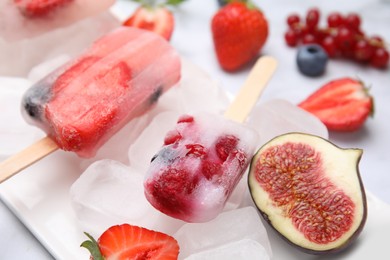 Photo of Tasty refreshing fruit and berry ice pops on light table, closeup