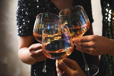 Photo of Women clinking glasses with white wine, closeup