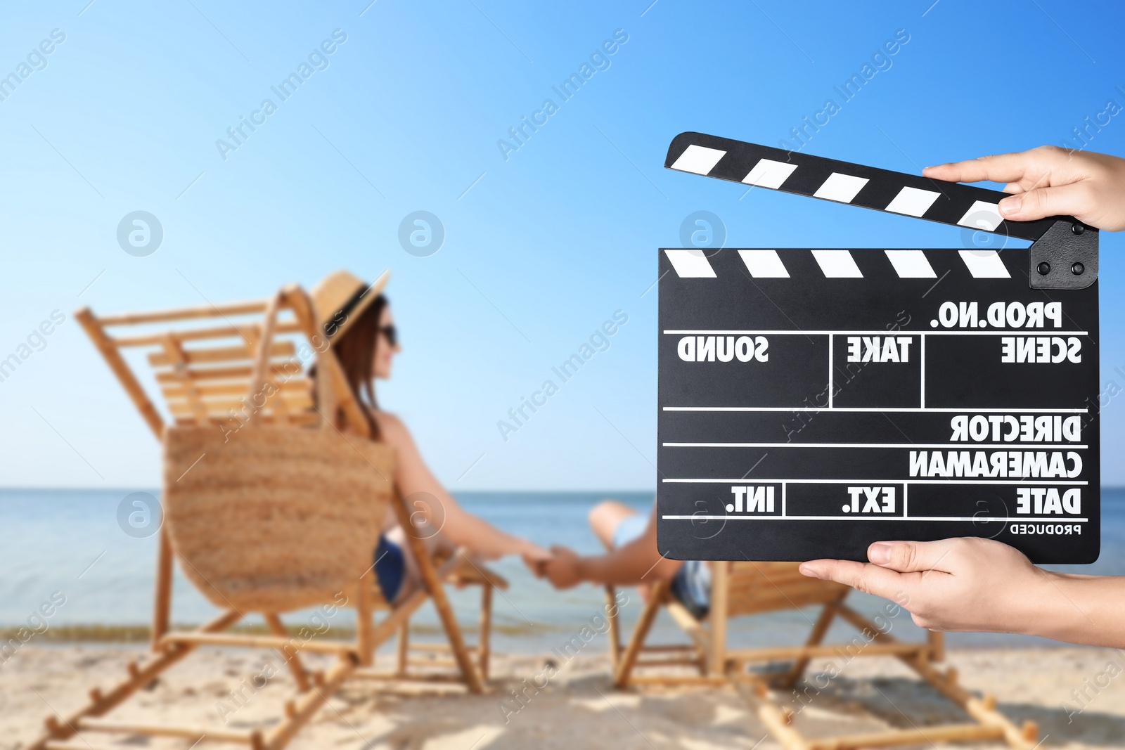 Image of Assistant holding clapperboard and people relaxing in deck chairs on beach, closeup. Cinema production 