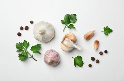 Flat lay composition with green parsley, pepper and garlic on light background