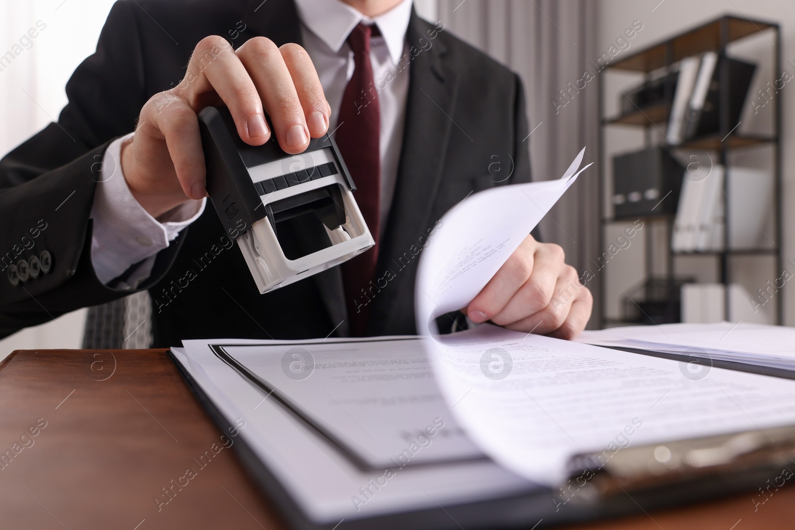 Photo of Notary stamping document at table in office, low angle view