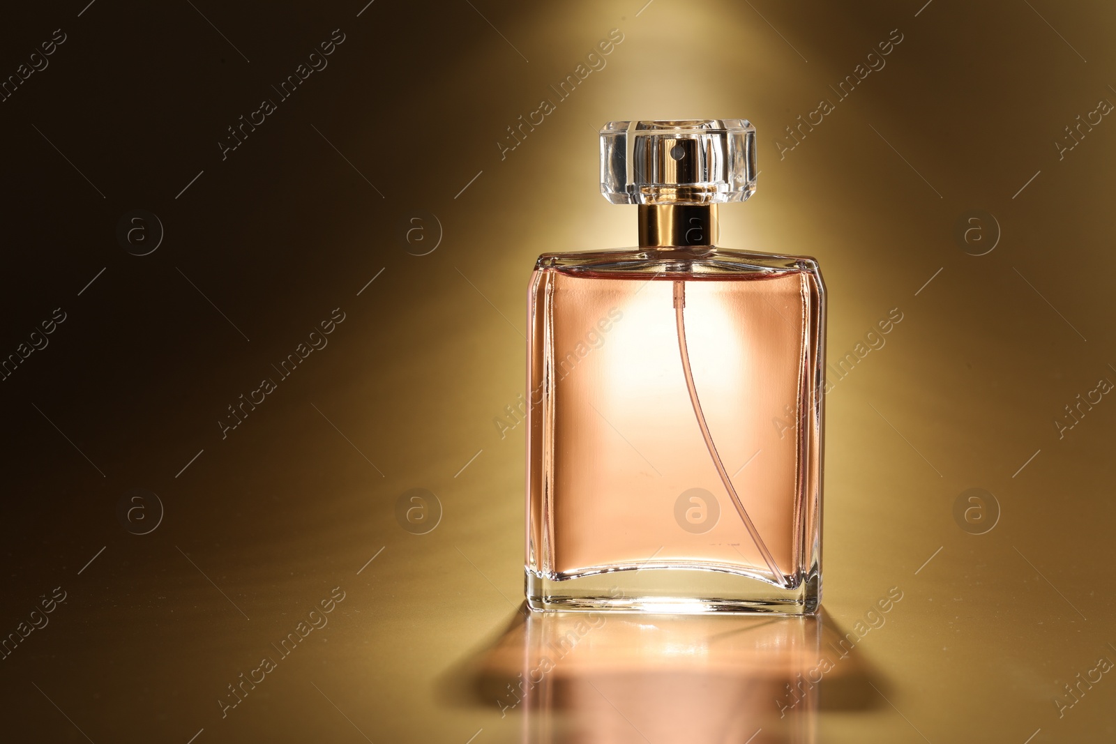 Photo of Luxury women's perfume. Sunlit glass bottle on golden background, space for text