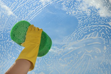 Photo of Woman cleaning glass with sponge indoors, closeup
