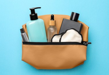 Preparation for spa. Compact toiletry bag with different cosmetic products on light blue background, top view
