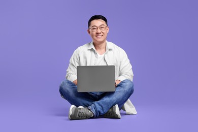 Photo of Happy man with laptop on lilac background